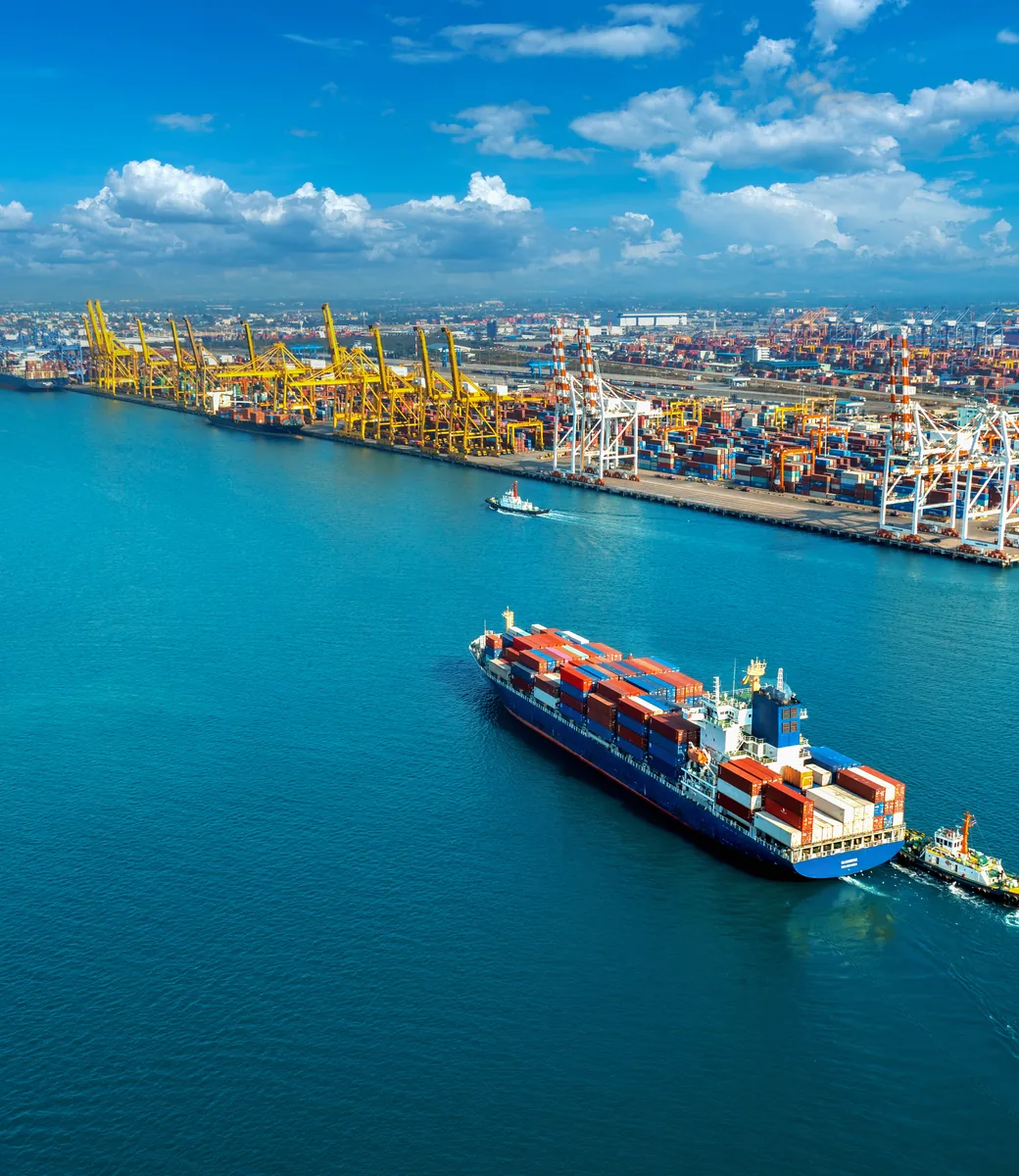 Vista aérea de um porto de contêineres com navio cargueiro partindo em rota para a União Europeia